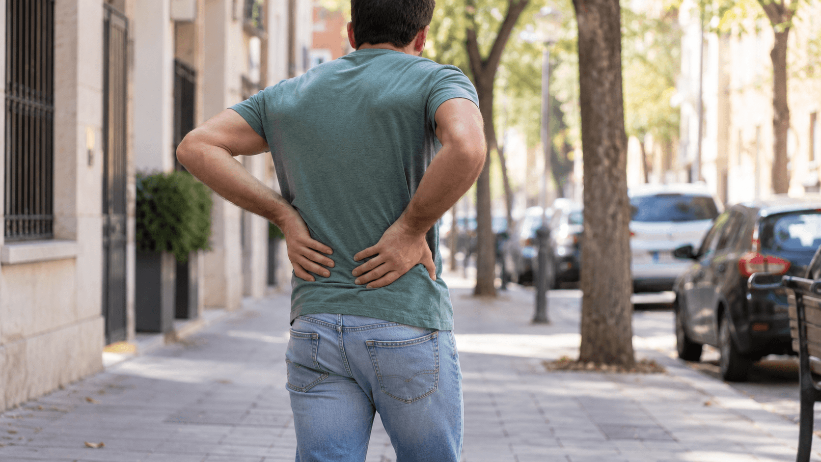 Hombre con las manos en la zona lumbar por dolor de espalda al caminar